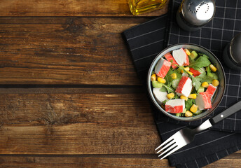 Tasty crab stick salad served on wooden table, flat lay. Space for text