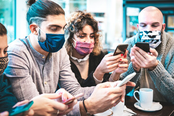 Worried people with face mask checking news on mobile smart phones at coffee break - New normal...