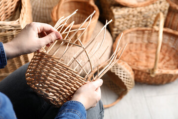 Woman weaving wicker basket indoors, closeup view - obrazy, fototapety, plakaty