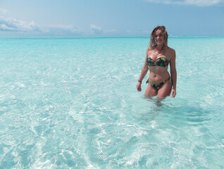 Blonde woman standing in shallow water of tropical sea