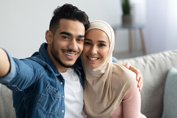 Obraz na płótnie Canvas Beautiful muslim man and woman in hijab taking selfie