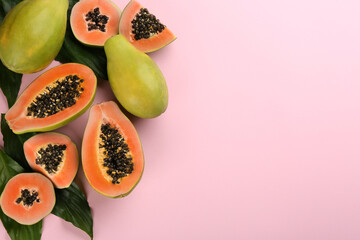 Fresh ripe papaya fruits with green leaves on pink background, flat lay. Space for text