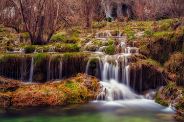 Cascada de agua en nacimiento río Cuervo entre musgo verde