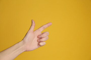 Naklejka premium Woman pointing at something on yellow background, closeup. Finger gesture