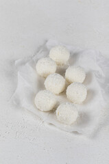 Fototapeta na wymiar Cottage cheese balls with almonds and coconut chips on paper on a white background