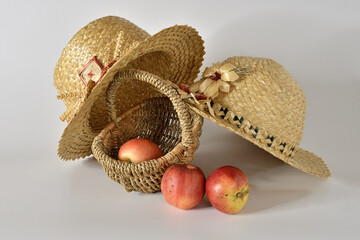 Straw hats, a basket, and three apples.