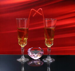
Valentine's day wine glasses filled with drink with straw on red background