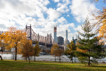 Queensbridge Park in Long Island City Queens New York during Autumn with Colorful Trees and the Queensboro Bridge along the East River