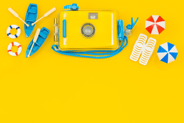 Miniatures of beach equipment and a stylish camera for underwater photos, umbrellas, boats, sun loungers. blank yellow background with space for text, concept, Sunny beach vacation.