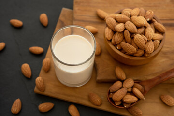 Almond milk with almond in a wooden spoon and bowl on a wooden (selective focus; close-up shot)