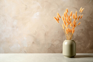 Dried flowers in vase on table against beige background. Space for text © New Africa