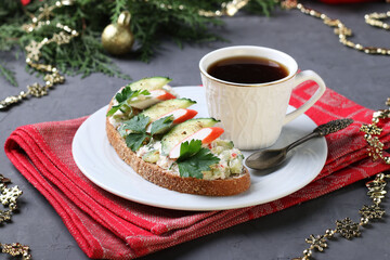 Homemade sandwich with crab sticks, cucumber, cream cheese and a cup of coffee on dark background. © Anzhela