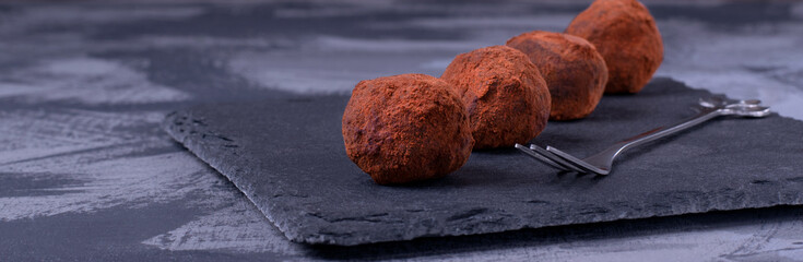Chocolate truffles with cocoa powder on the stone plate. French cuisine dessert. Wide banner