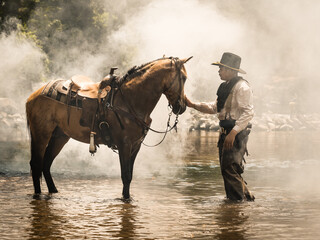 A young cowboy rested with a horse in the stream after he finished showering the horse