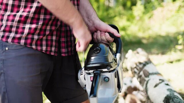 Lumberjack starts working, turn on ignition, pulls starter of chainsaw engine and starts sawing. Favorite work at summer sunny day in the forest. High quality 4k footage