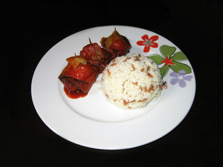 plate with rice and garbage kebab on a black background.