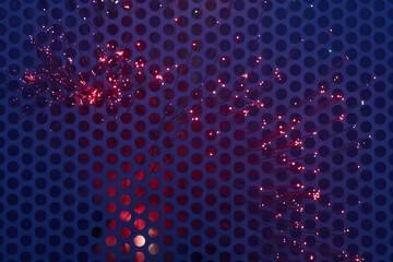 Lichtwellenleiter leuchten mit farbigem Licht durch ein Gitter hindurch.