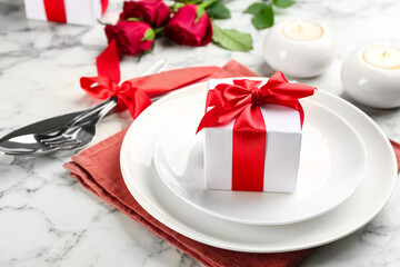 Beautiful table setting for Valentine's Day dinner with gift box on white marble background