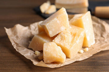 Pieces of delicious parmesan cheese on wooden table, closeup