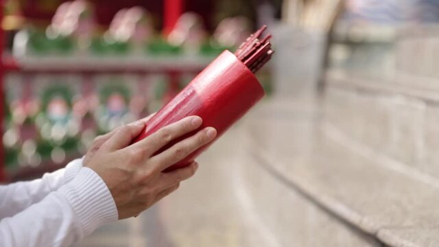 Close up asian buddhist hand predicting fortune by shaking chi chi stick to forecast the future , It is a Buddhist belief