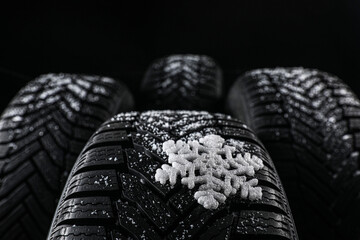 Set of new winter tires on black background, closeup