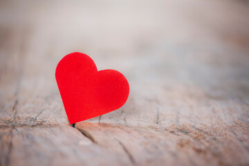 Fototapeta premium Signal of Valentine's Day red heart from paper on wooden table, against defocused lighting.