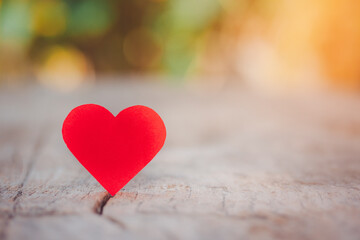 Fototapeta premium Red heart cut off red paper on wooden table, Valentine's Day, giving love to someone isolated on bokeh background.