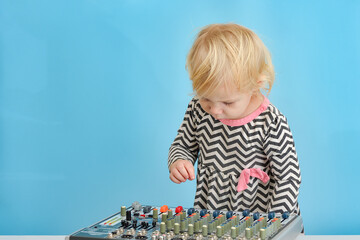 A small child looks at a music mixing console in surprise.
