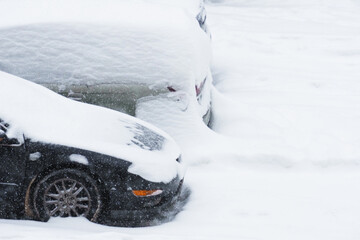 Cars covered with snow in a parking lot during a blizzard, winter natural disaster