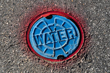 Red and blue water access point in the asphalt