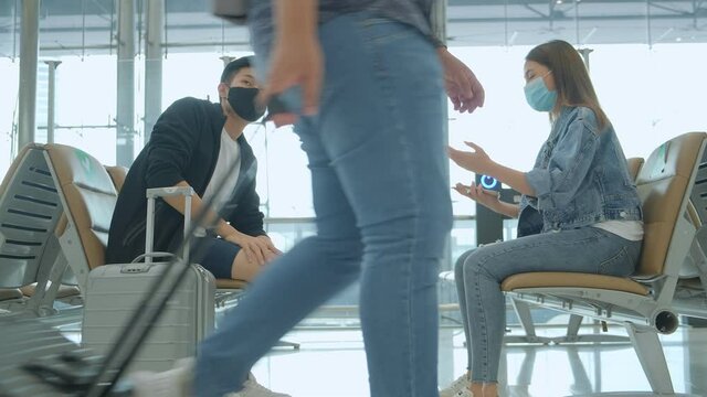 friends asian tourist traveller wear protective face mask  have conversation wait flight schedule in new space social distancing in airport terminal new normal lifestyle
