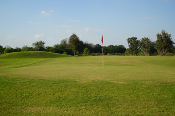 Obraz premium Background of evening golf course has sunlight shining down at golf course in Thailand. Nice scenery on a golf course at a late summer afternoon.