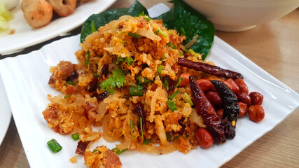 Spicy Salad of Curried Rice Croquettes Fermented Pork, Ginger, dry chili and Peanuts on white plate or dish at Thai restaurant. Asian food.