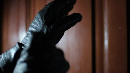 Criminal putting on leather gloves, closeup