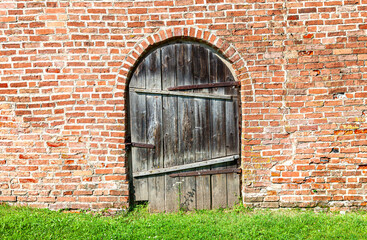 Old wooden gate with forged massive metal hinges