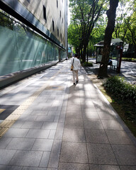 木漏れ日の歩道を歩く男