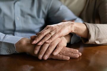 Close up mature spouses holding hands, enjoying tender moment, loving elderly wife supporting comforting husband, expressing empathy and understanding, trusted relationship in marriage concept