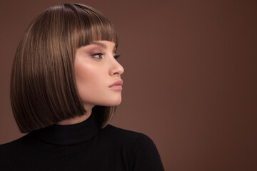 Portrait of a beautiful brown-haired woman with a short haircut on a brown background