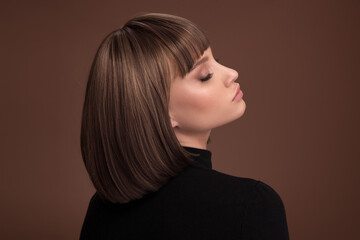 Portrait of a beautiful brown-haired woman with a short haircut on a brown background - 408101469
