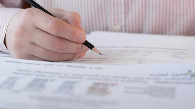 Businessman manager holding pencil for reading signing in paperwork or documentation files front view