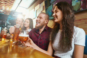 Friends laughing and joking while drinking ale in pub