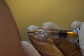 close up of a hand holding an injection next to the skin of an arm