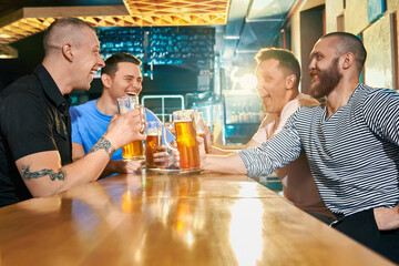 Side view of happy male company enjoying evening in pub