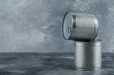 Closed tin cans with vegetables placed on marble background
