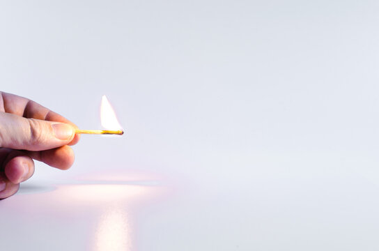 hand holding a burning match on a white background copy space concept