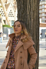 Portrait photo of a beautiful model leaning against a tree in the park.