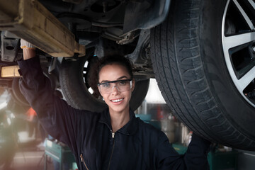 Female auto mechanic work in garage, car service technician woman check and repair customer car at...