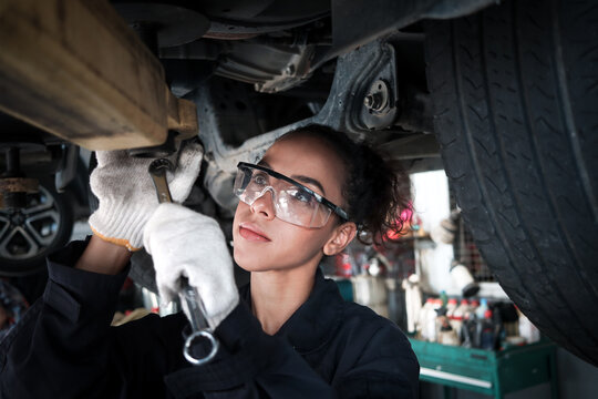 Female auto mechanic work in garage, car service technician woman check and repair customer car at automobile service center, inspecting car under body and suspension system, vehicle repair service sh