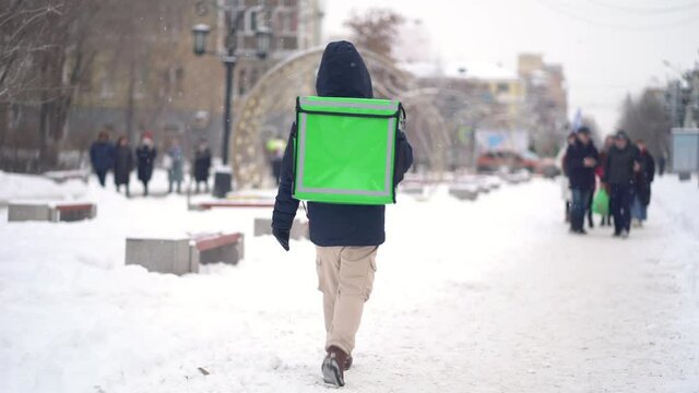 Courier is delivering food with backpack at winter.