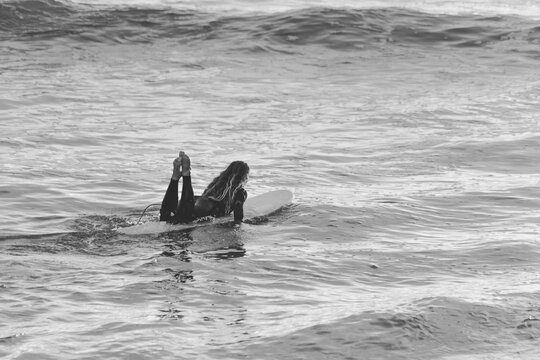 Black and white surfer girl padling 